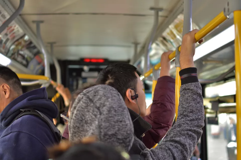 Bus riders standing on crowded city bus, holding top rail